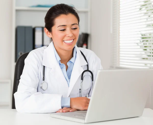 Good looking female doctor working with her laptop while sitting