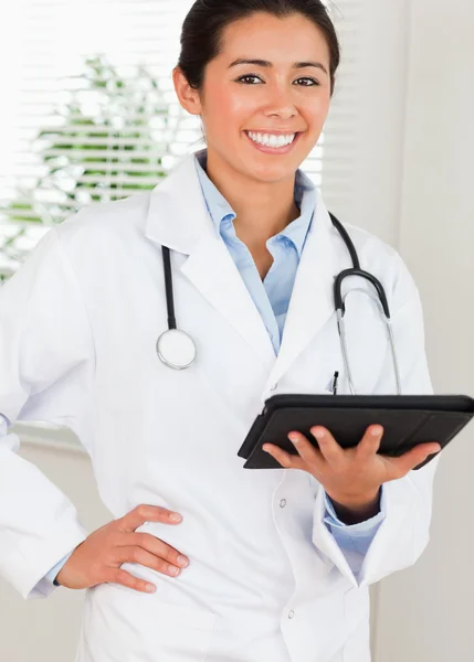 Beautiful female doctor with a stethoscope holding a notebook wh