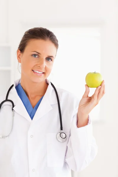 Gorgeous brunette doctor looking at a green apple