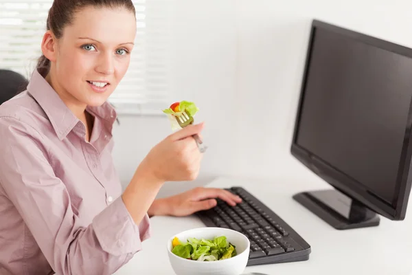 Businesswoman in office eating salad