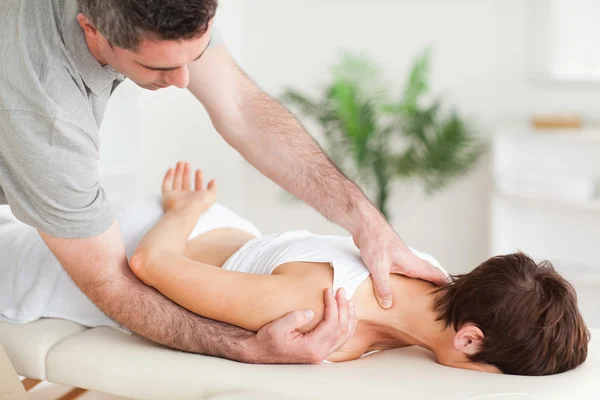 Chiropractor stretching a woman\'s shoulder