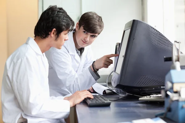 Student pointing at something on a monitor to his classmate