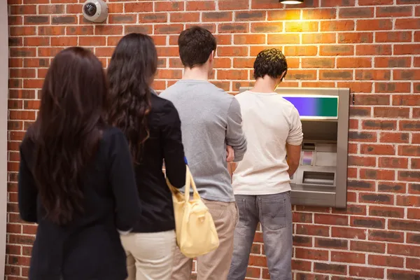 Young queuing to withdraw cash