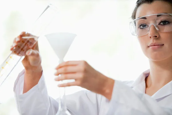 Scientist pouring liquid in a funnel