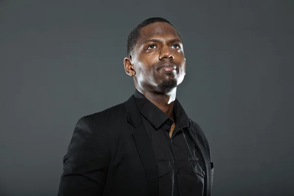 Cool black american man in dark suit. Studio fashion shot isolated on grey background.