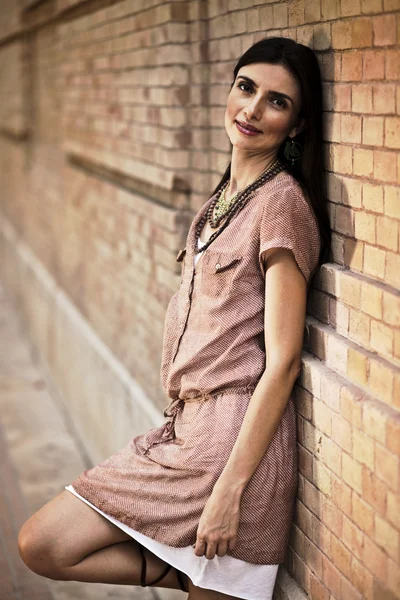 Beatiful woman leaning against a brick wall