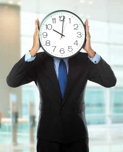 Man covering his face with clock