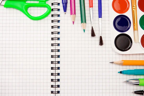 Pencils, felt pens, paint brush and scissors on paper