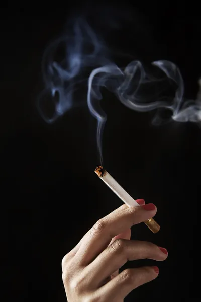 Female fingers holding burning cigarette