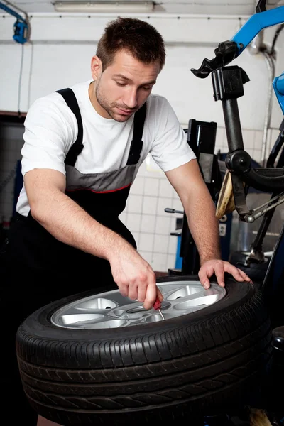 Mechanic fixing tyre in car service