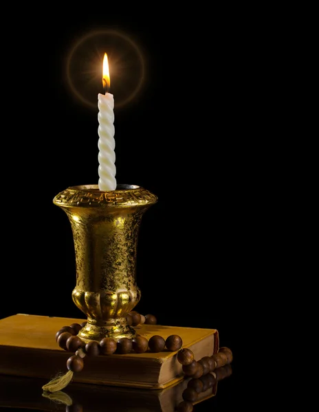 Candle with rosary and antique book