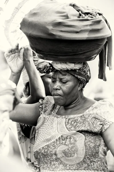 A big Ghanaian lady with a basin of stuff over the head