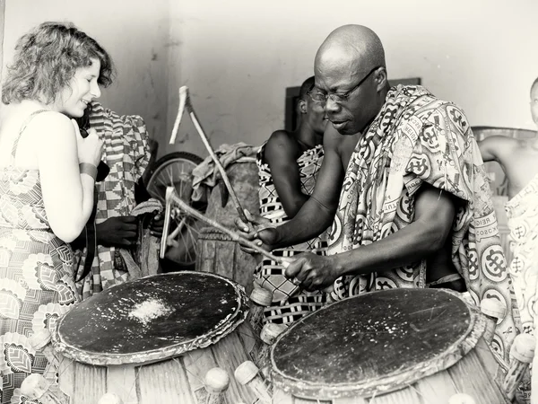 A man in glasses from Ghana plays the drums