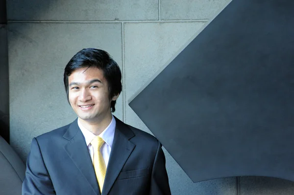 Asian business man dressed in suit and tie, smiling.