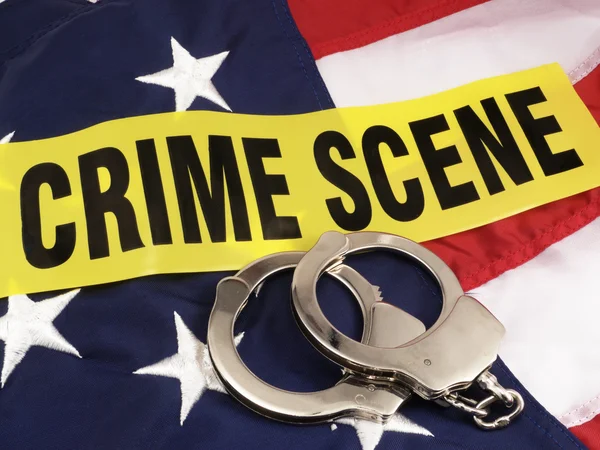 Crime Scene Tape And Hand Cuffs Over American Flag