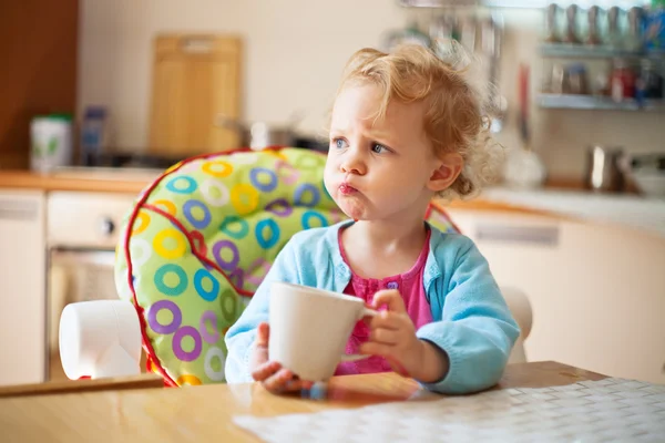 Portrait of little girl having drink in the kitchen