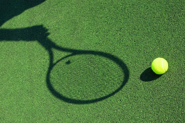 Shadow of a tennis racket in hand with a ball