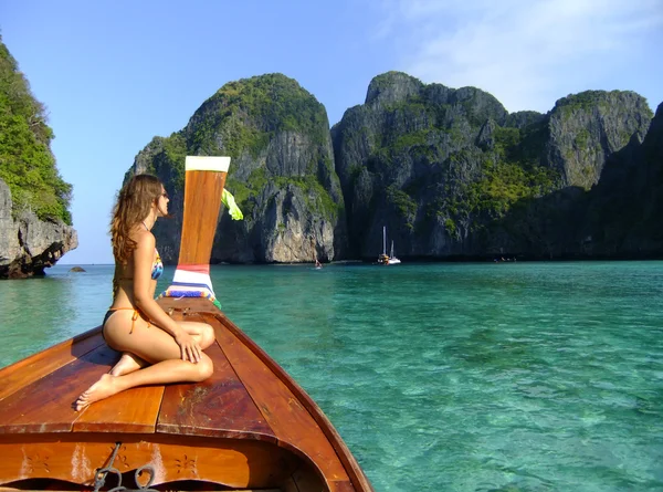 Young woman in bikini sitting on a stern of longtail boat, Phi Phi Lei island, Thailand