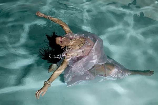 Woman floating under water arms out