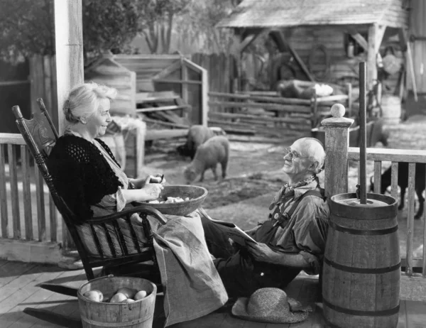Elderly couple on porch of farmhouse