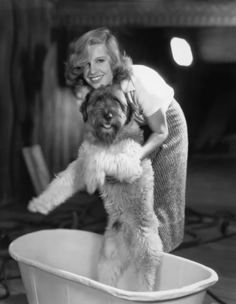Woman bathing dog in tub