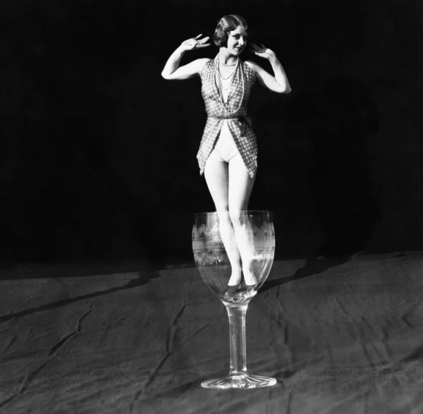 Tiny woman standing in wineglass