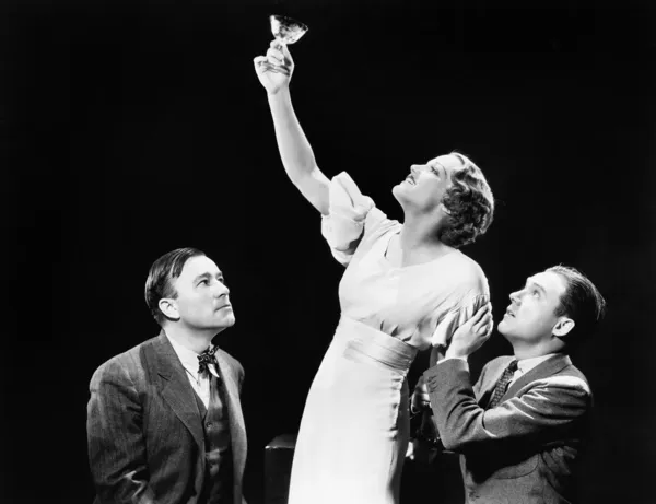 Two men supporting a woman lifting her wine glass