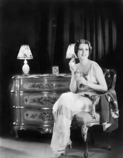 Elegant woman in an evening dress applying perfume to her neck