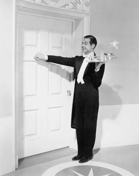 Waiter with tray knocking on a door