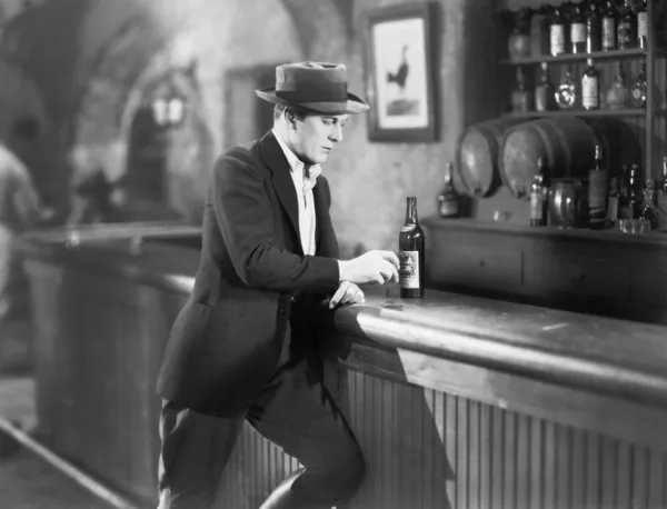 Lonely man standing at a bar counter with a drink
