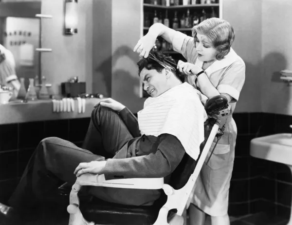 Woman barber cutting a man\'s hair