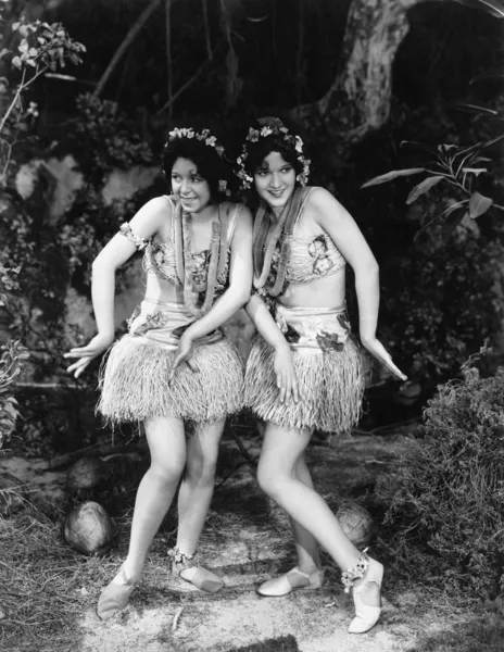 Two women dancing in grass skirts