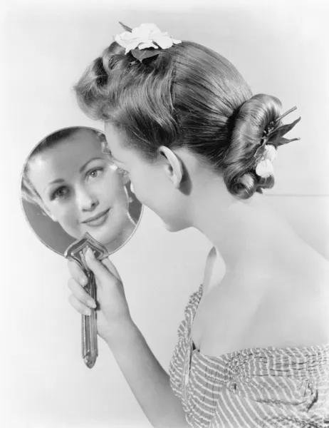 Reflection of a young woman, looking in a mirror
