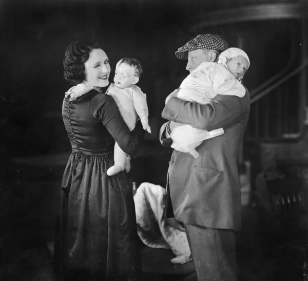 Father holding baby and mother holding a doll
