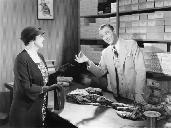 Woman buying fabric from a sales clerk at a department store