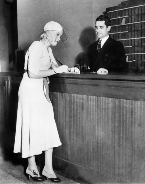 Woman standing at the counter of a hotel where she is checking in