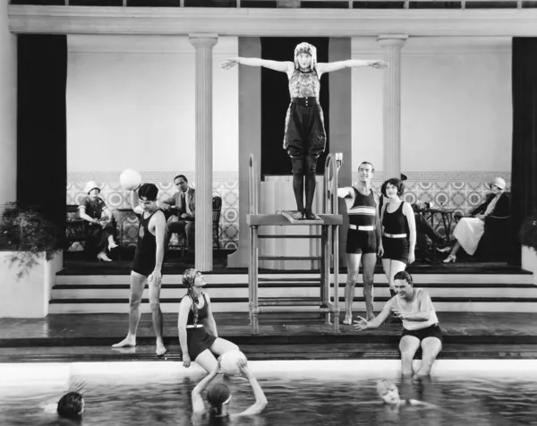 Young woman standing on a diving board surrounded by a group of playing