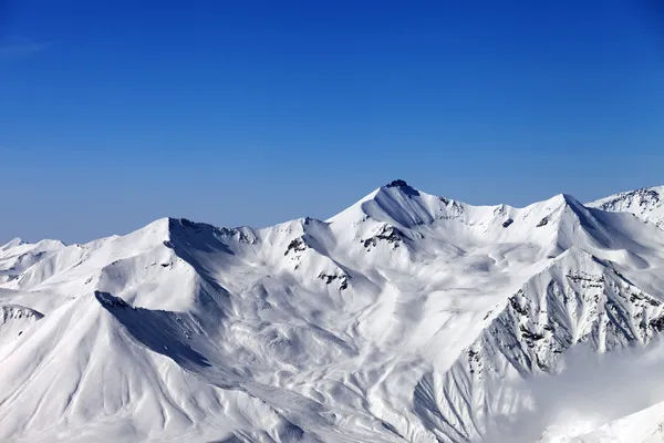 Besneeuwde bergen en de blauwe hemel — Stockfoto