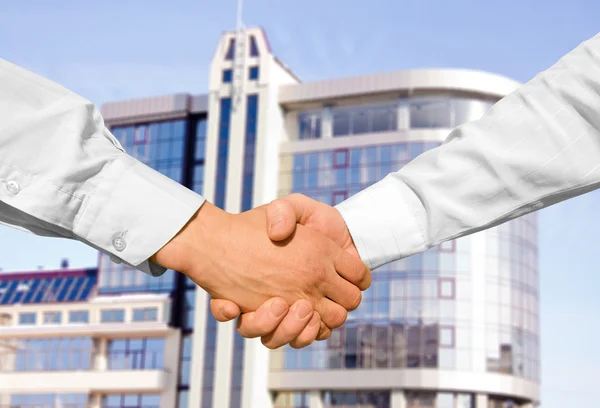 Handshake s moderní mrakodrapy jako pozadí — Stock fotografie