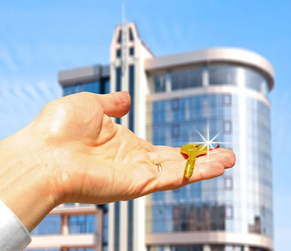 Fastigheter koncept. nycklar i fingrar med byggnad — Stockfoto