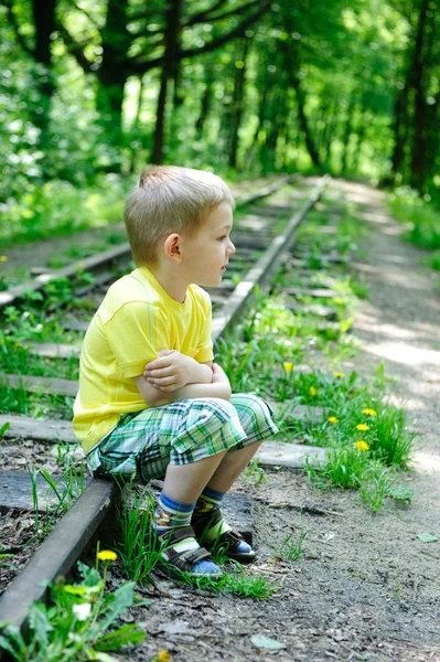 Мальчик сидит на рельсах — стоковое фото
