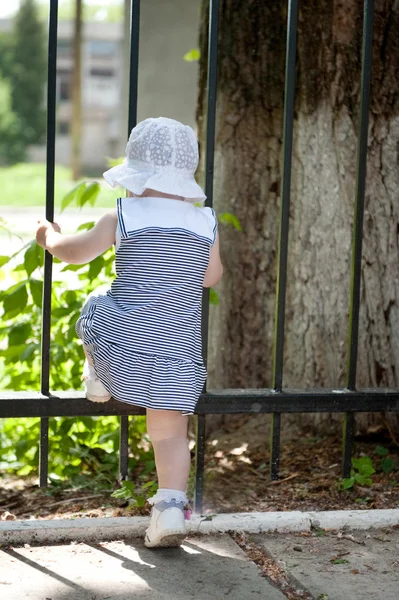 Маленькая девочка рядом с забором — стоковое фото
