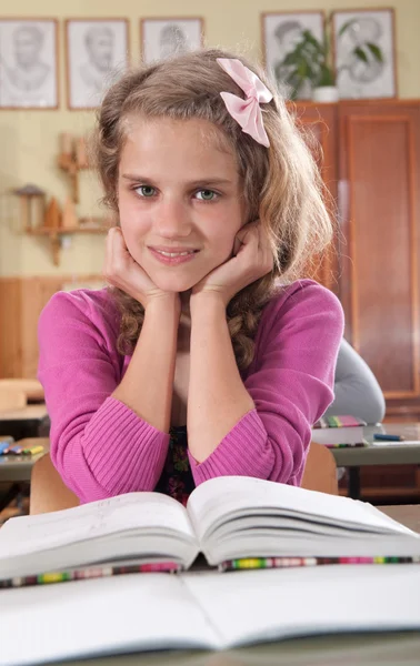 Мила дівчина читає книгу в класі в школі — стокове фото