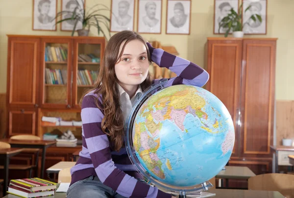 Hübsches Mädchen mit Globus im Klassenzimmer — Stockfoto