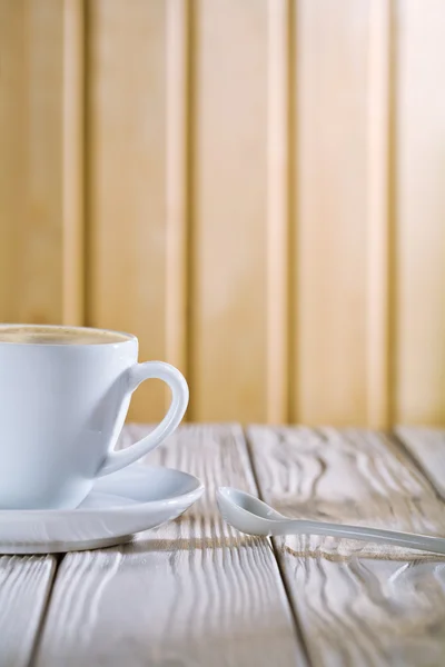 Біла чашка кави і ложка на старому столі — стокове фото