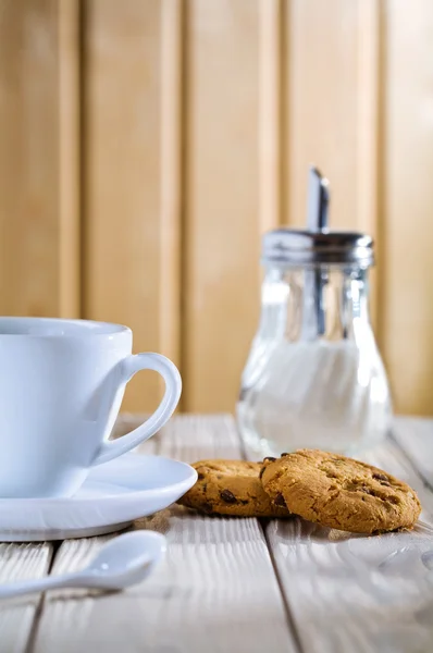 Taza con galletas y dispensador de azúcar en la mesa — Foto de Stock