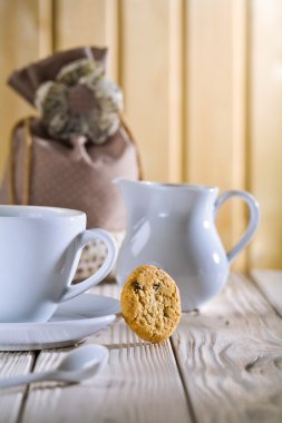 White cup and jug with bag on table clipart