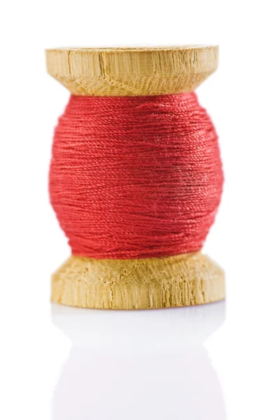 Pequeno carretel de costura com fio vermelho — Fotografia de Stock