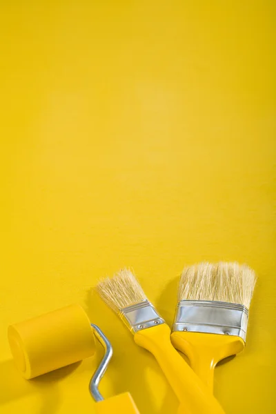 Copyspace image Pincéis e rolo de pintura sobre um fundo amarelo — Fotografia de Stock