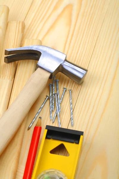 Claw hammer with nails and pencil on level — Stock Photo, Image